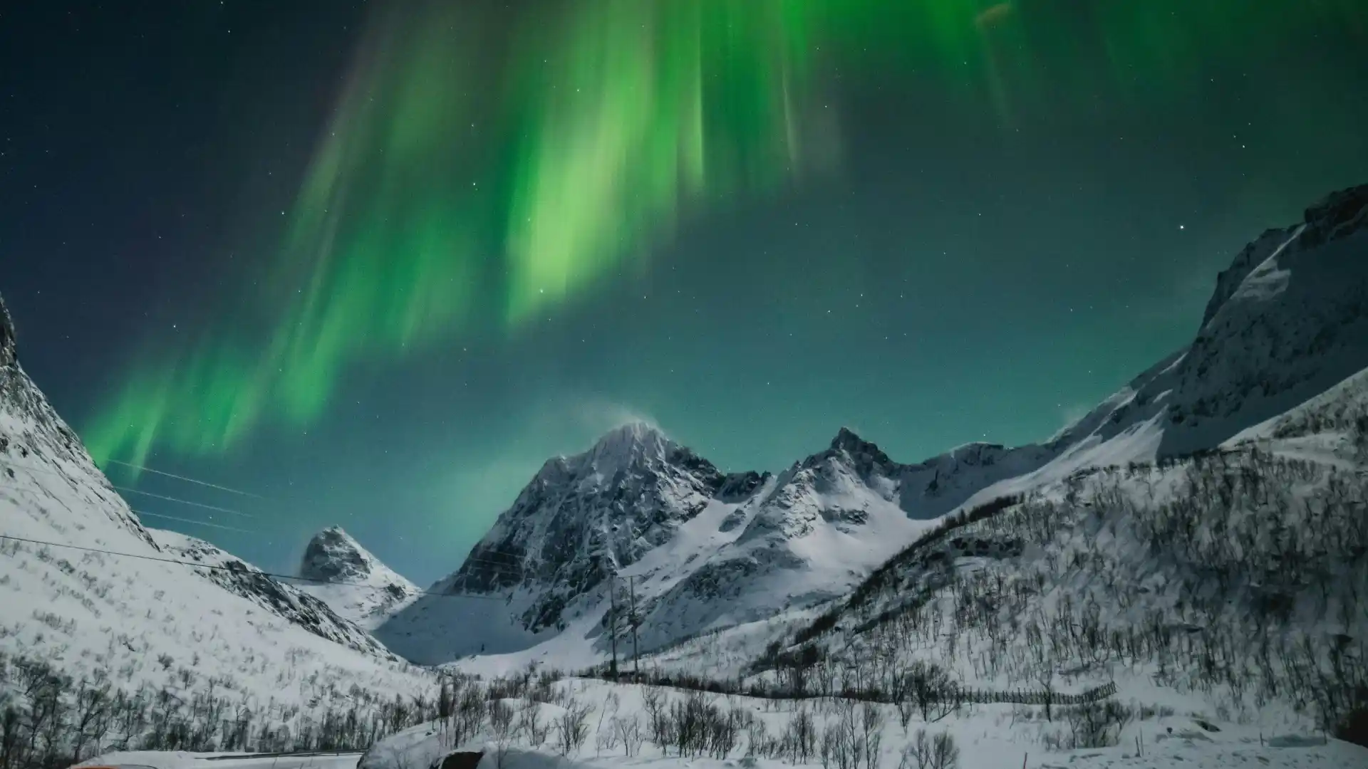 The Northern Lights glowing over snowy mountains in Alaska.
